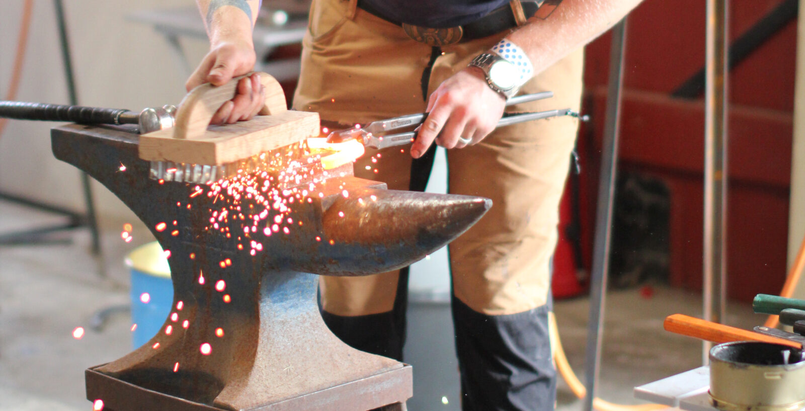 En person deltar i en smidestävling och använder städ med en glödande järnsko på