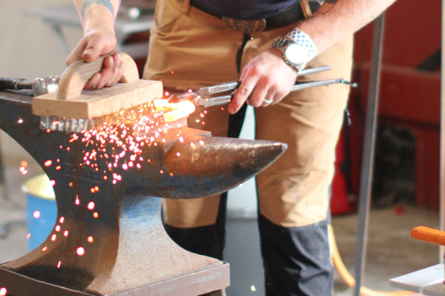 En person deltar i en smidestävling och använder städ med en glödande järnsko på