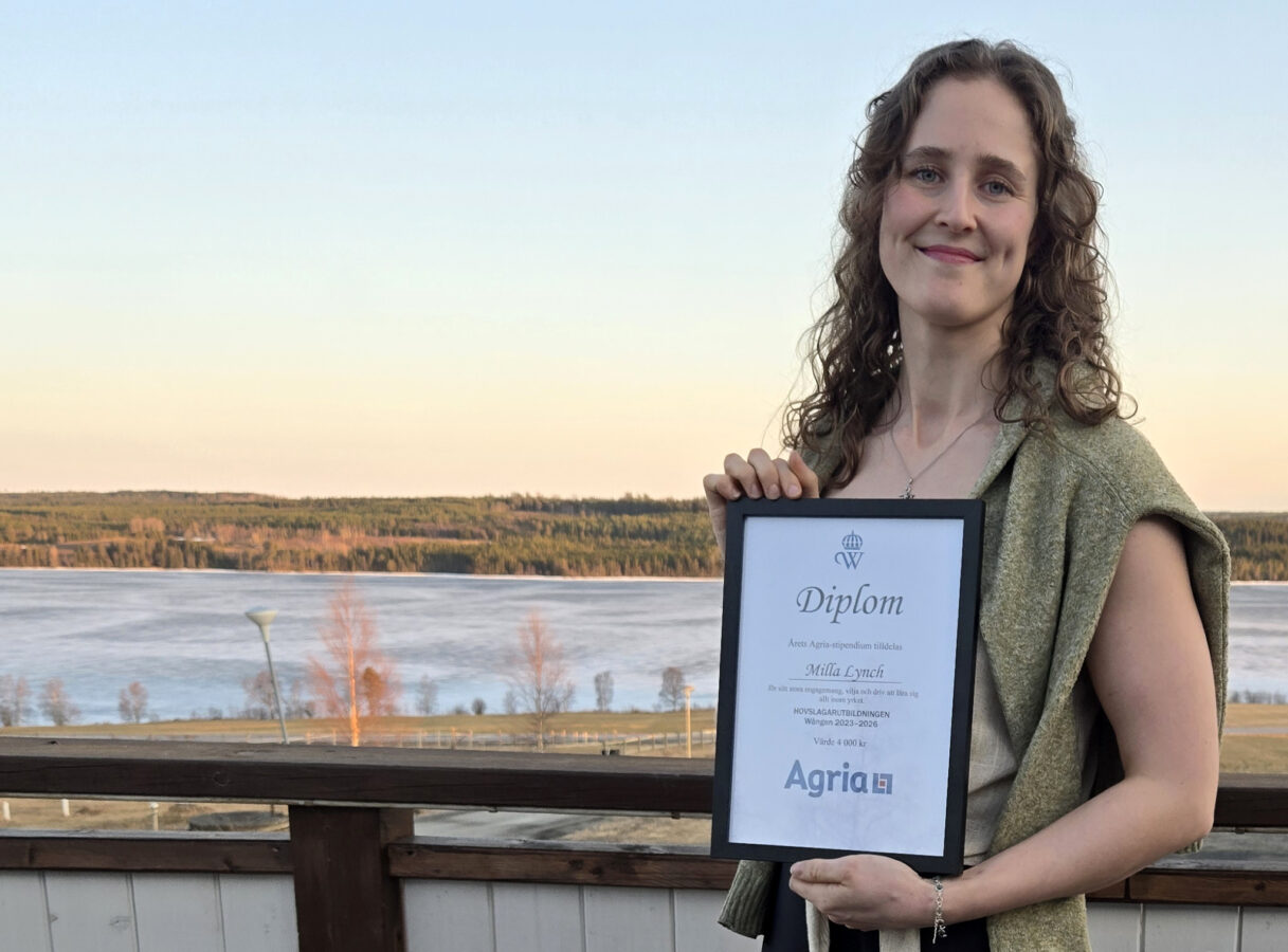 Ung kvinna står utomhus en vårkväll i Jämtland. I handen håller hon ett inramat diplom från Agria