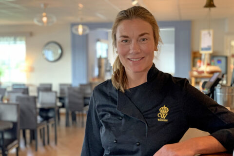 Annika Gripenberg står i restaurangens matsal, i svart serveringsjacka med Wångens gula emblem på.